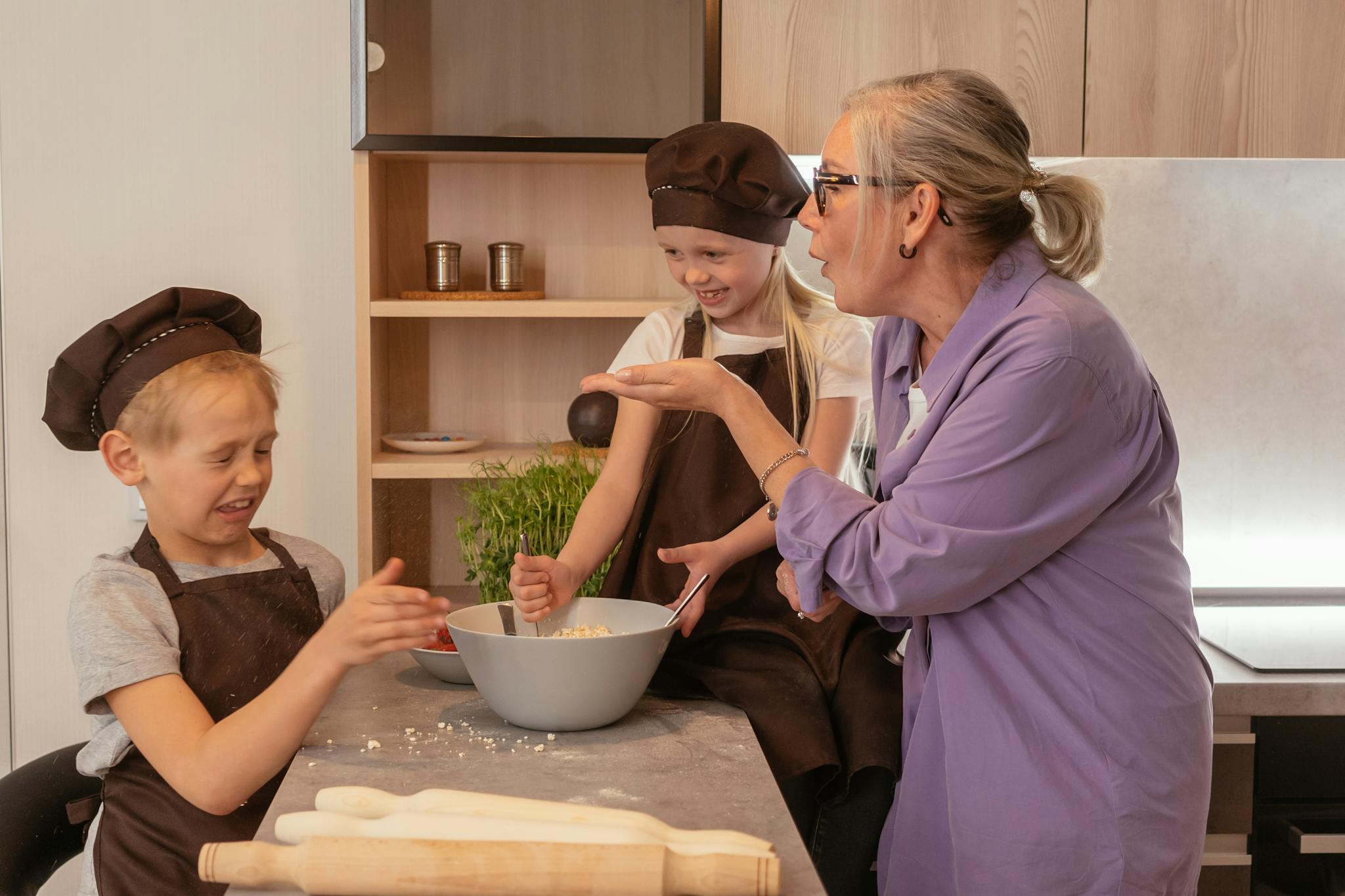 A joyful family moment of a grandmother cooking with her young grandchildren in a modern kitchen.